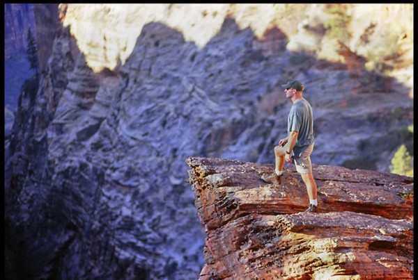 A hiker stands on a cliff overlooking Zion Canyon in Zion National Park as lead photo for a daily Bible devotional