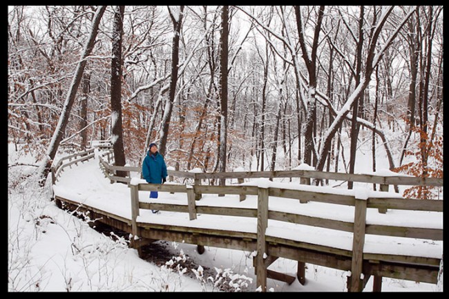 A woman walking on a snow covered boardwalk at Fontenelle Forest