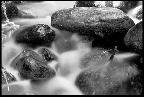 A black-and-white photograph of water flowing through the rocks of the Calypso cascade in Rocky Mount national Park