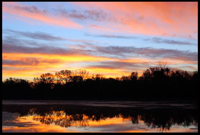 Bible Verse of the Day: A red, blue and orange sky at sunrise, Fontenelle Forest, Bellevue, Nebraska and Psalm 113:3. The name of the lord is to be praised