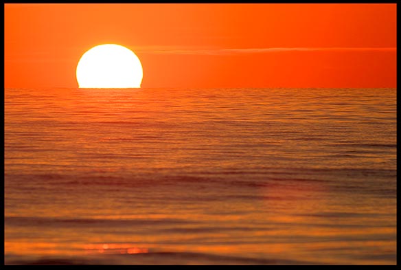 The sun sits on red horizon of water and sky at sunrise of the Melbourne, Florida coast. Does nature reveal any Biblical themes?