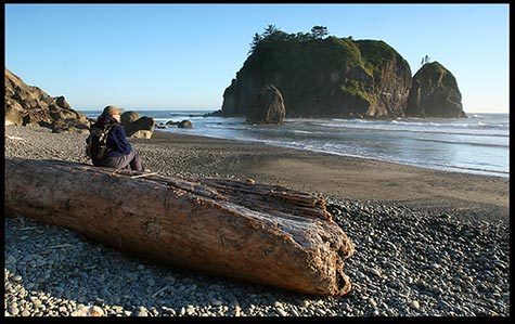 A woman enjoys the sunset on the beach in Olympic National Park, Washington State