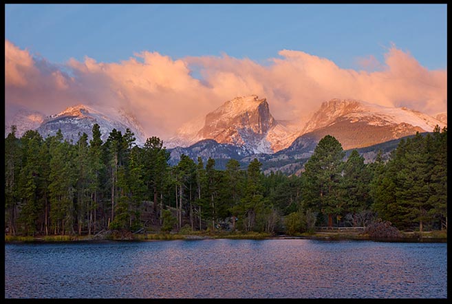 Sunrise strikes a red glow on the clouds and mountains above Sprague Lake in Rocky Mountain National Park, Colorado and Amos 4:13, He who forms mountains bible verse