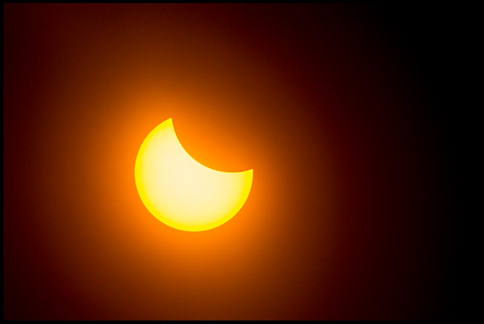 The moon begins to block out the sun during the solar eclipse 2017 as seen from near Grand Island Nebraska and Isaiah 13:10 Bible verse God of judgement