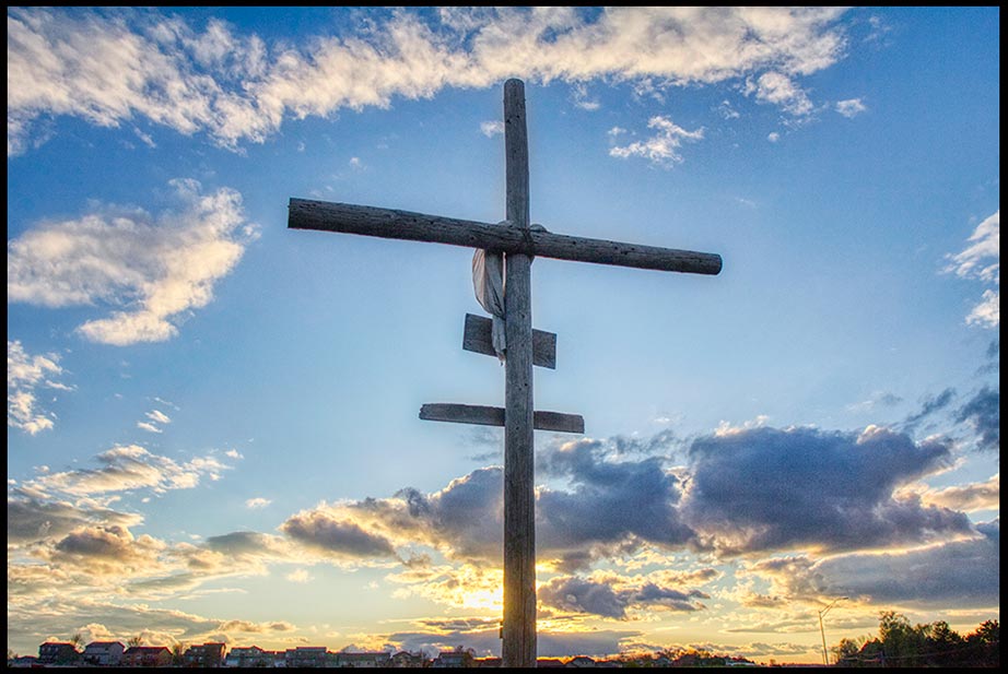 A cross silhouetted against a blue sky and white clouds near sunset, Papillion, Nebraska Bible Verse of the Day: Mark 8:34, 35. Christ call us to take up our Cross