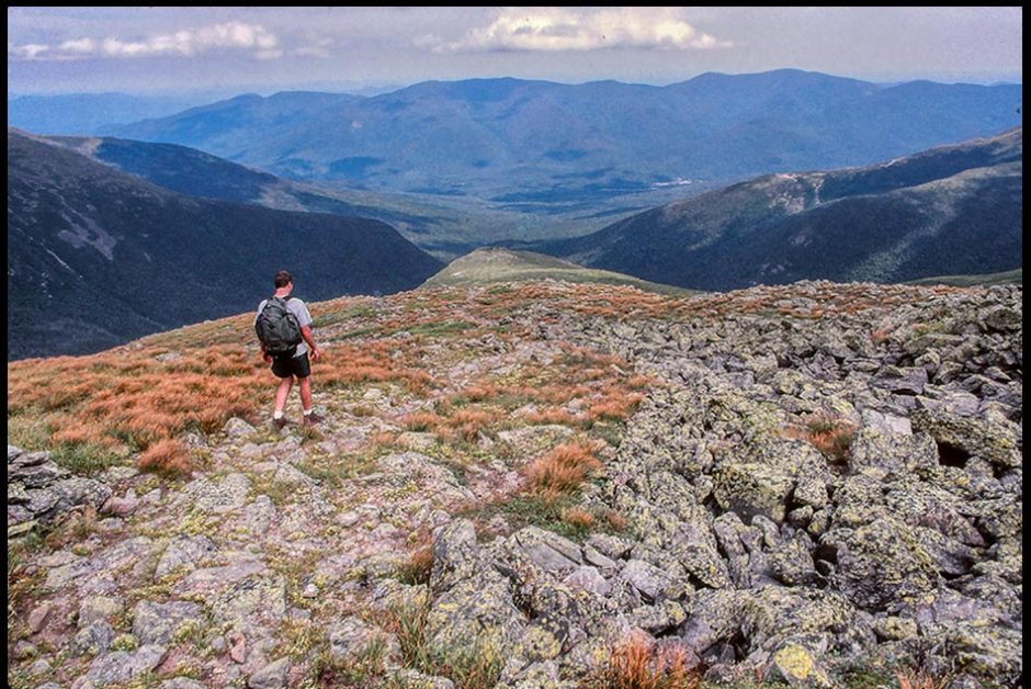Hiker walks down a mountain in the White Mountains, New Hampshire and Psalm 119 Bible verse. Make me walk in the path
