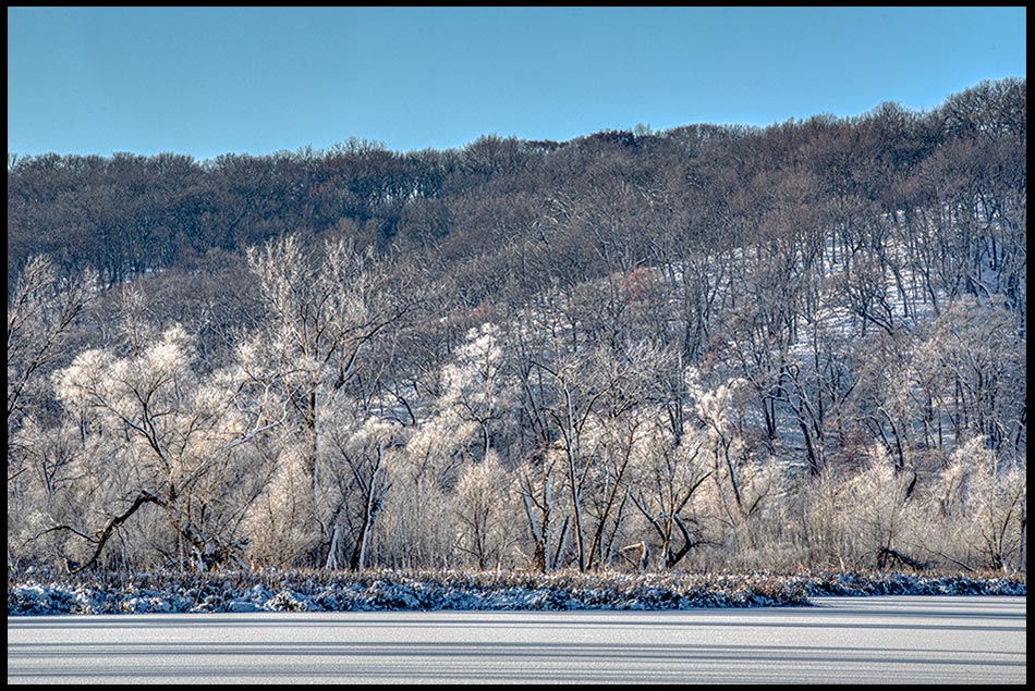 A frozen lake below hill covered with snow and hoarfrost covered trees, Fontenelle Forest, Nebraska. Bible Verse of the Day: Job 38:29-30 God and His greatness