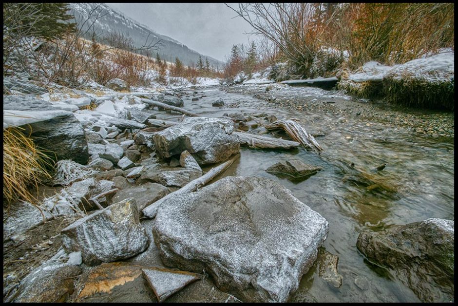 Small snow flakes cover a rock in thawed mountain stream in late Winter Alberta, Canada. Bible Verse of the Day Psalm 147:18 frozen hearts