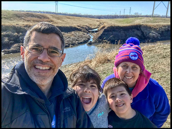 A outdoor selfie of a family of four (a mom and dad with their son and daughter). Head to the outdoors to free your anxiety from covid-19 