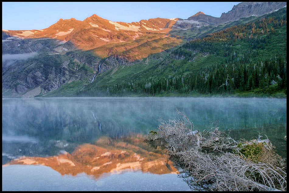 The alpine glow on mountains reflect in Gunsight Lake at dawn in Glacier National Park, Montana and Psalm 145 about God's mighty works.
