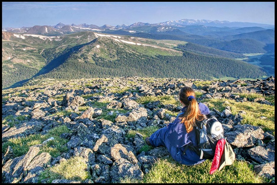 A woman hiker sits on the Mountain side of Mount Chapin of the Mummy Range, Rocky Mountain National Park, Colorado. Bible Verse of the Day: Deuteronomy 34 promise land