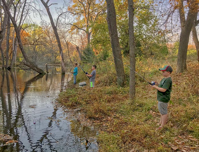 Boys fishing on Duck Creek under trees in fall colors, Duck State Park, Nebraska.
