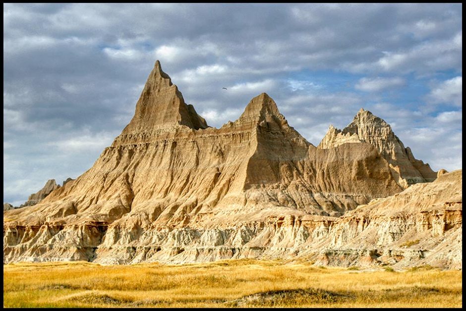 a bird flies over desert rock formations, Badlands National Park, South Dakota and Psalm 68:4-5. Bible verse, God leads through deserts