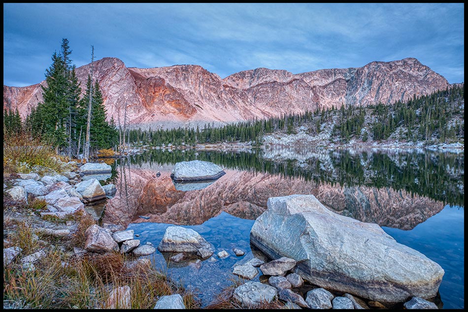 Mountains of the snowy Mountain Range reflect in the still waters of Mirror Lake. Bible verse of the day Psalm 18:46, God our rock of protection