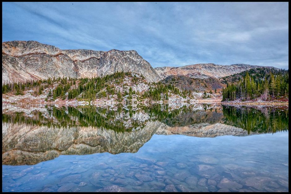 The mountains of the Snowy Mountain Range of Wyoming reflect in Mirror Lake. Bible verse of the day, draw near to God Hebrews 10:22