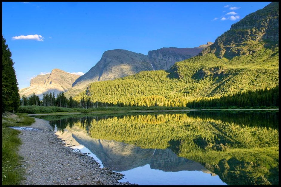 Mountains reflect in a lake in glacier national Park. Bible verse of the day 1 Chronicles 29:19. praise you glorious name 